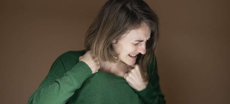 Woman in green sweater feeling pain.