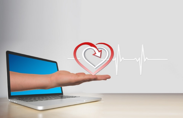 An illustration of a hand holding a heart shape emerging from a laptop, symbolizing technology-assisted interventions for substance abuse.