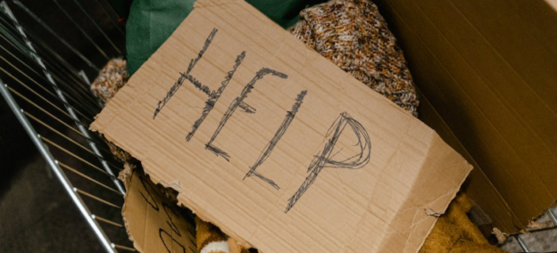 A piece of cardboard that reads “help”, illustrating the intersection of drug addiction and homelessness in WV.