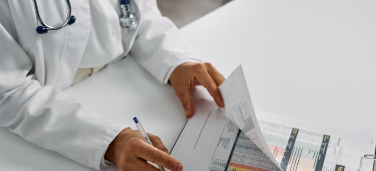 A close-up of a medical professional going through patient records, illustrating how MAT benefits for addiction recovery rely on close supervision.