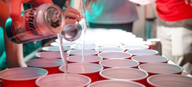 A close-up of cups being filled at a party, outlining peer pressure as one of the factors contributing to cocaine abuse.