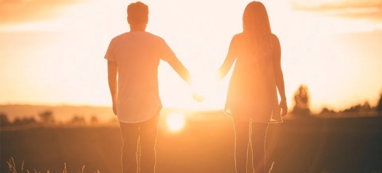 A couple holding hands at sunset.