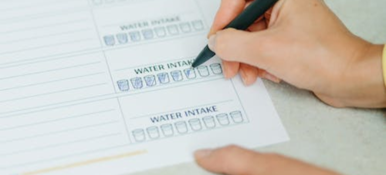 A close-up of a person noting down their water intake.