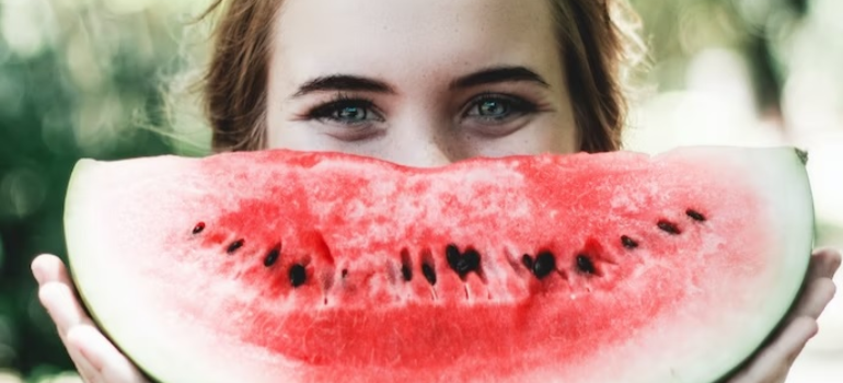 A smiling woman holding a watermelon, symbolizing the importance of nutrition in alcohol addiction treatment.