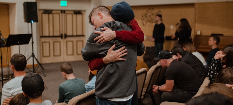 Two people hugging during addiction recovery group therapy 