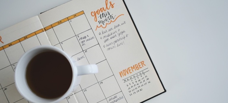 Cup of coffee on an open planner used for setting goals, representing the need for positive thinking in addiction recovery