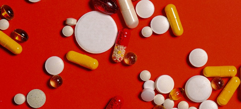 Different pills and tablets on a red surface