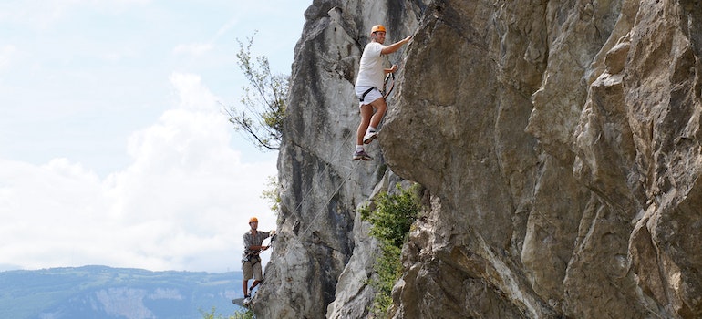 Two man climbing a rock during wilderness therapy for addiction treatment in West Virginia