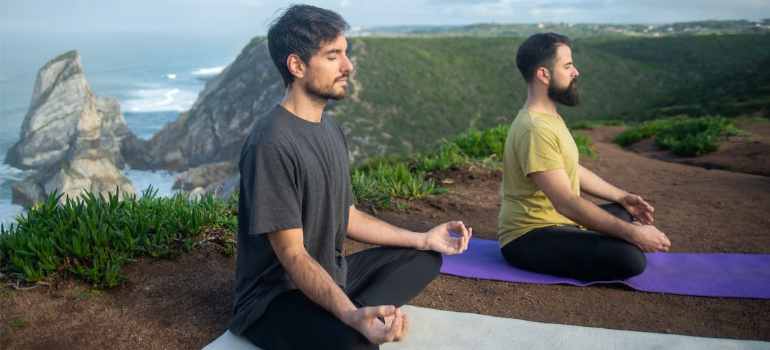 Two men doing yoga outdoors.