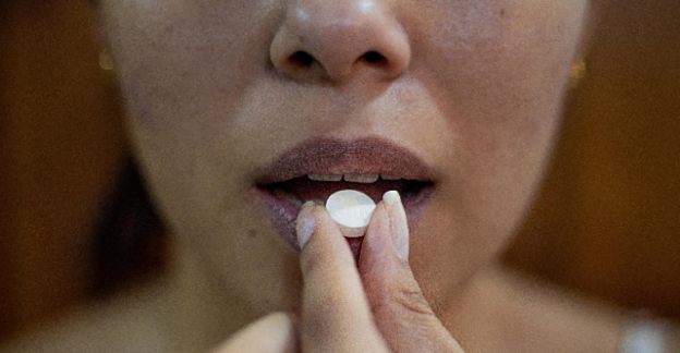 A woman taking a white pill representing medications used in addiction treatment in West Virginia