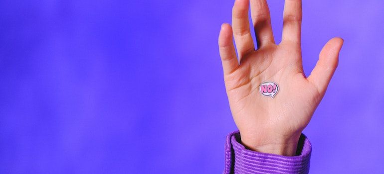 Person's palm with a NO sticker on it to emphasize denial, one of the signs of a high-functioning addict