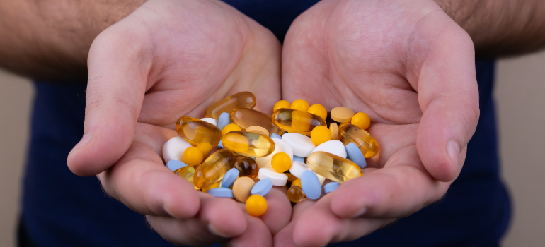A man holding in his hands a lot of different yellow drugs and pills.