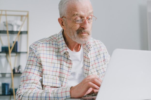 An older man looking at his laptop representing Alcohol Addiction Impact on Older Adults in West Virginia