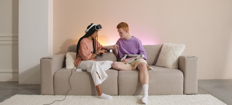 A man and a woman using a VR set while sitting on a couch.