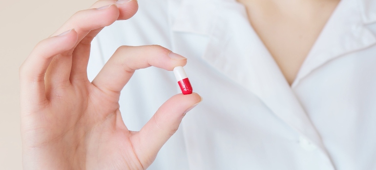 A person holding a red and white pill