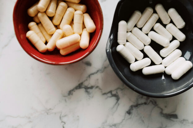 Two bowls filled with capsules on a marble surface, representing medications that might be used during the opioid withdrawal timeline.