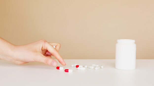 A person taking a red and white pill for medication-assisted treatment options in Parkersburg
