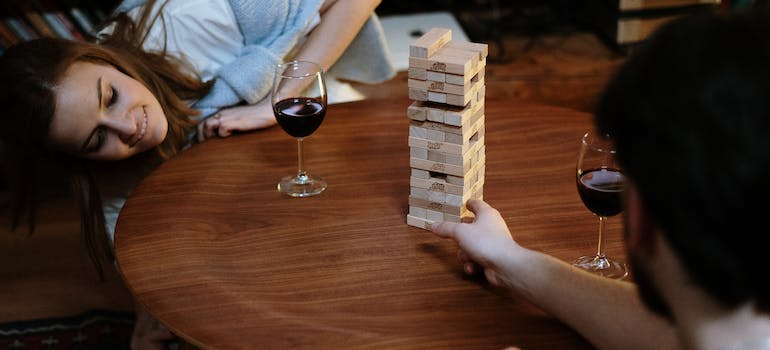 Two people drinking wine and playing Jenga as one of Drinking Games Among WV Students