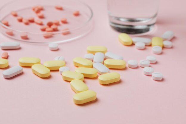 Different types of pills on a pink background