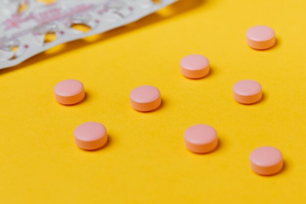 Pink pills on yellow surface