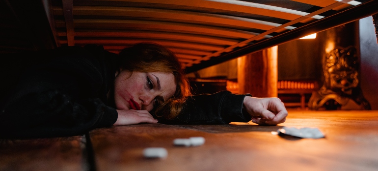 Anxious woman under the bed after using eutylone.