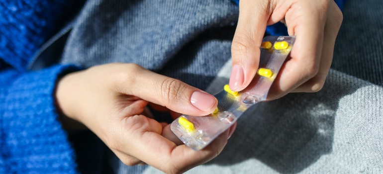 A person holding a blister with yellow pills