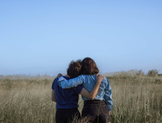 Two people hugging and looking at a field
