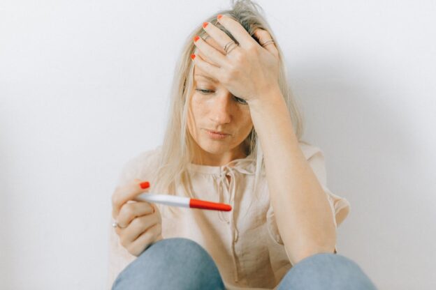 A sad woman looking at a pregnancy test