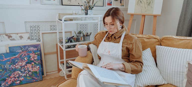 A woman sitting on the sofa and painting reflecting inner thoughts through Art Therapy