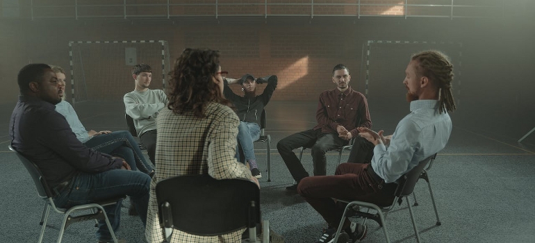 People sitting on chairs during group therapy for addiction in the first year of sobriety. 