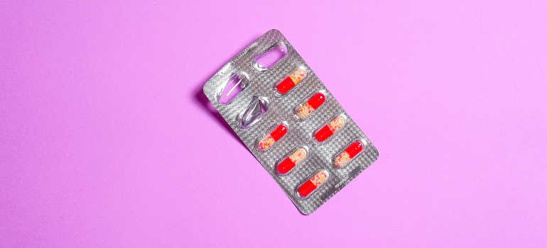 Red and beige pills in a blister pack on a pink background