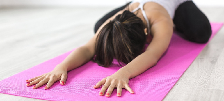 Person stretches their muscles on a yoga mat