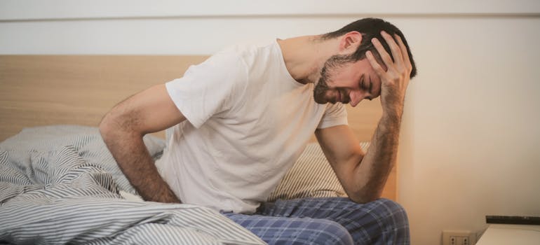 Man sitting on the bed having nausea as a result of combining alcohol and Codeine.