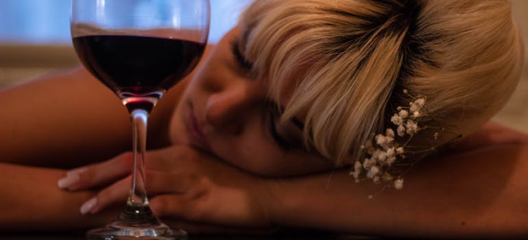 Woman slumped over a glass of wine.