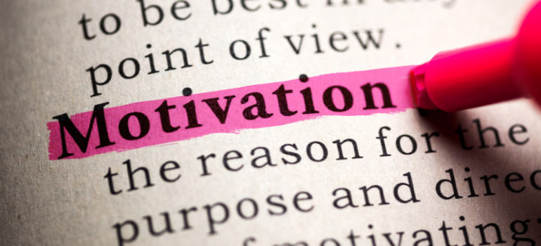 Someone highlights the word motivation in pink in a dictionary