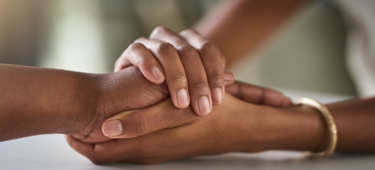 A child holds the hand of her parent while she supports her through addiction recovery