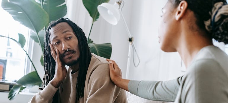 Woman talking to a man and touching his shoulder.