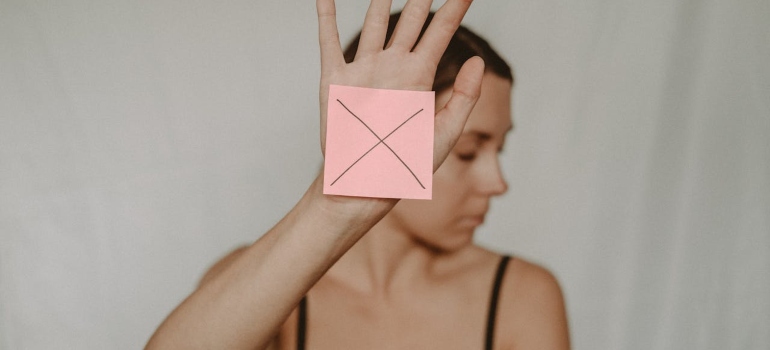 A woman holding an "x" sign symbolizing self-control, Drugs and Personality Types' reaction to self control