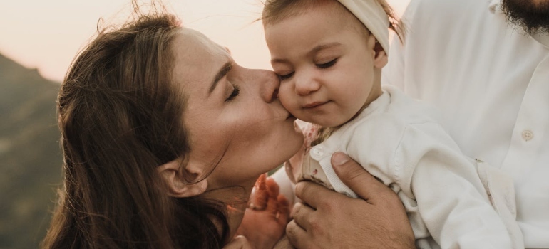 The picture of a mother kissing her child represents that you need to Tell Your Kids You Are Going to a Rehab Center, but do it gently and having in mind how old are they