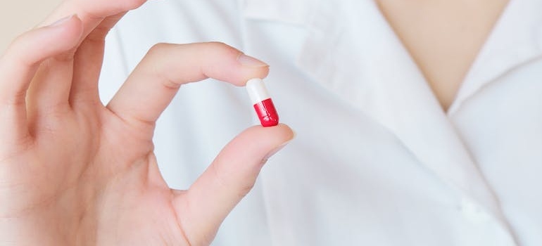 Doctor holding a white and red pill.