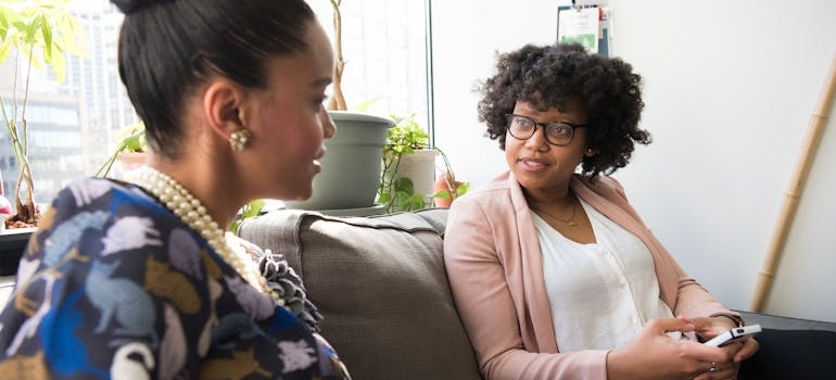 Two girls sitting on a couch and discussing serious topics.