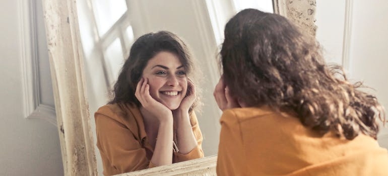 Woman looking at a mirror and smiling.