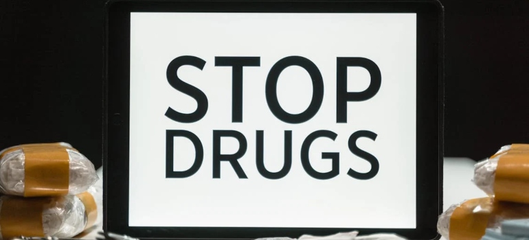 a tablet beside drugs on which is written "stop drugs"