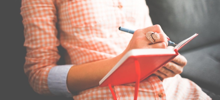 A woman journaling her thoughts in the red notebook