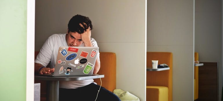 Man holding his head and looking at his laptop.