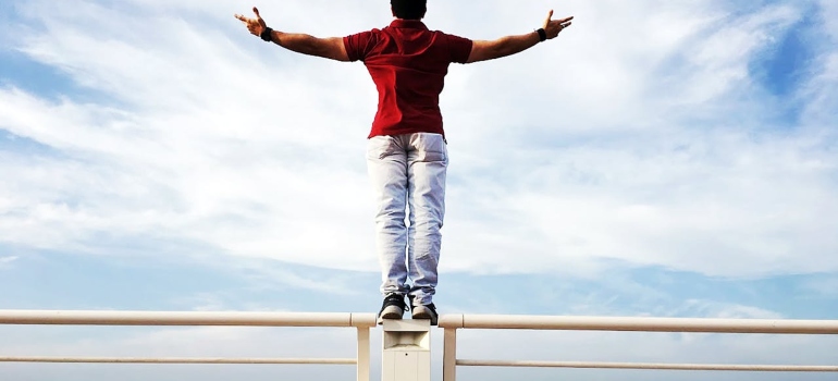 A man standing on the edge of some object underneath the sky