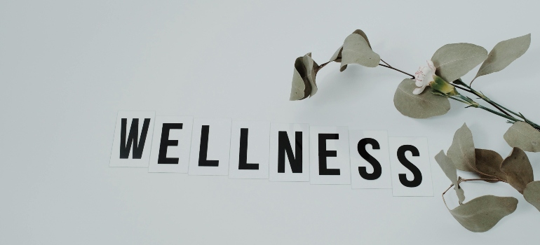 word wellness on white surface with a flower on the right side