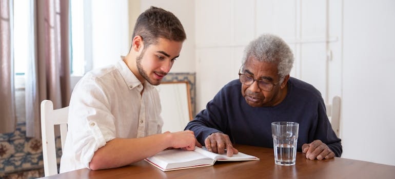 Grandson reading with his grandfather who suffers from Alzheimer's.