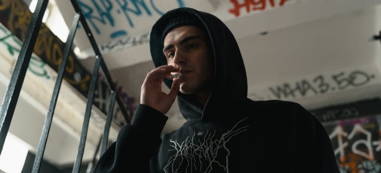 A man in a hoodie smocking cigarette