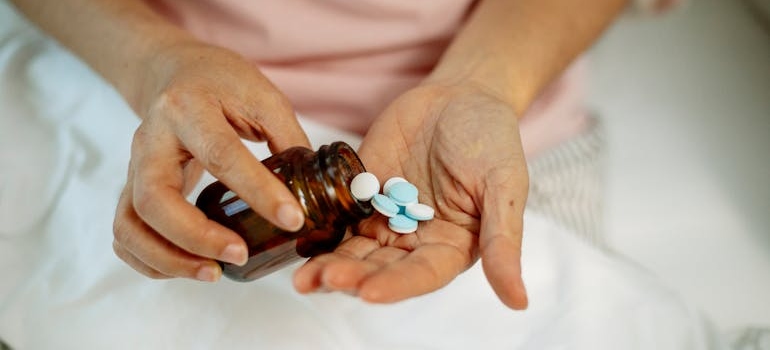 A woman taking pills from a jar after she relapsed, illustrating the recurring patterns of toxic behaviors in addiction.